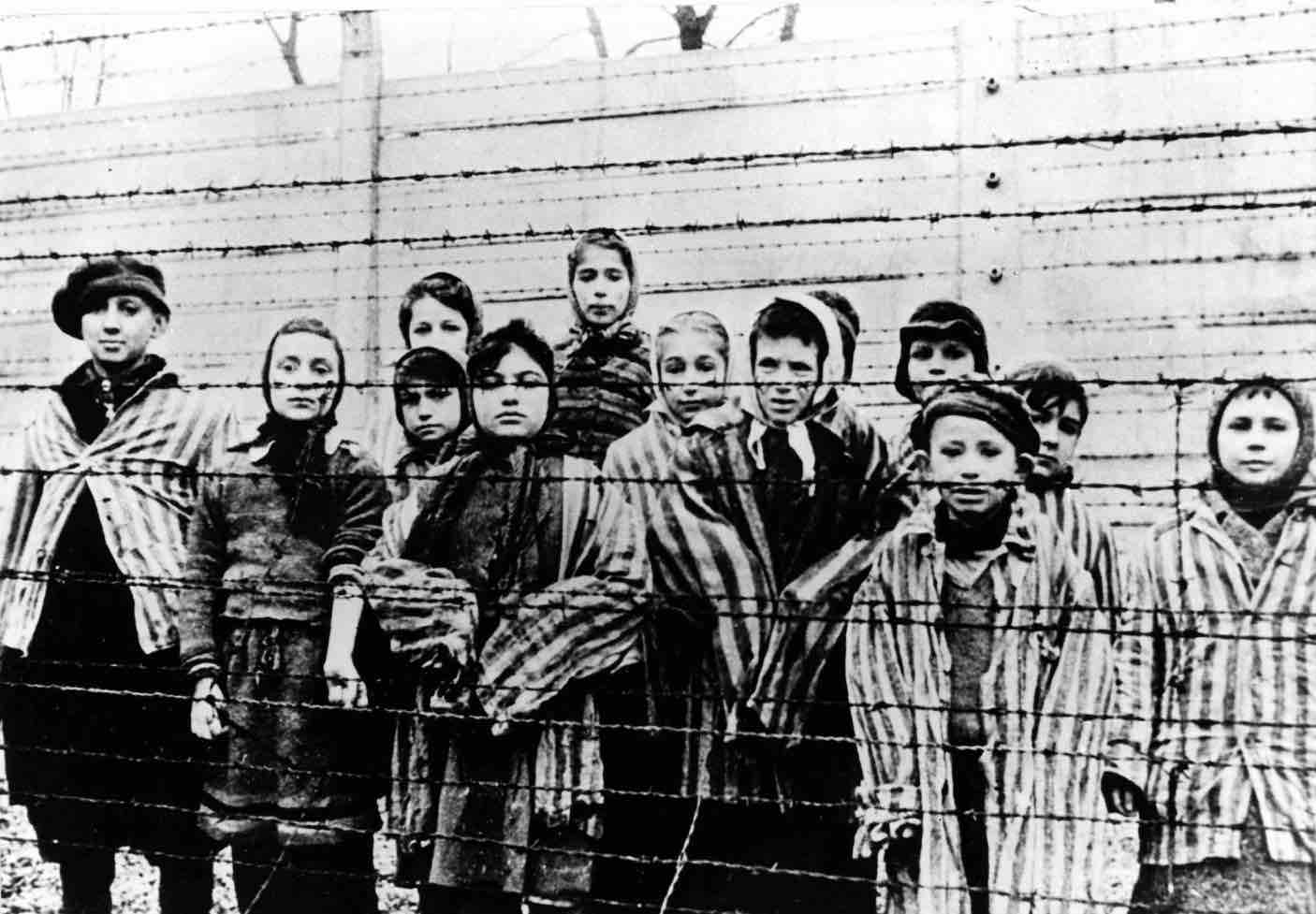 a-group-of-children-stand-behind-the-barbed-wire-fence-at-auschwitz-just-after-the-death-camp-was-liberated-by-the-soviet-army-in-january-1945-ap